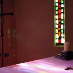 La lumière du soleil projette les couleurs du vitrail sur l'autel.
