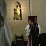 Au milieu, le père abbé vêtu d'une étole violette élève l'évangéliaire pour l'acclamation. La photo nous situe dans le chœur des moines, avec un frère qui apparait sur la gauche.