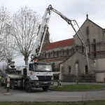 camion envoyant du béton dans l'église au bout d'un long tuyau