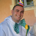 Un jeune frère est revêtu d'un chapeau pointu et d'un grand nœud papillon vert à pois blancs.