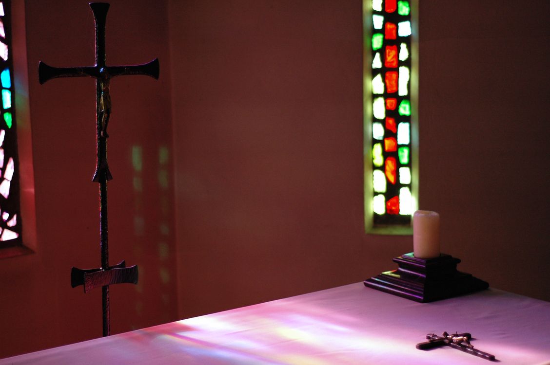 La lumière du soleil projette les couleurs du vitrail sur l'autel.