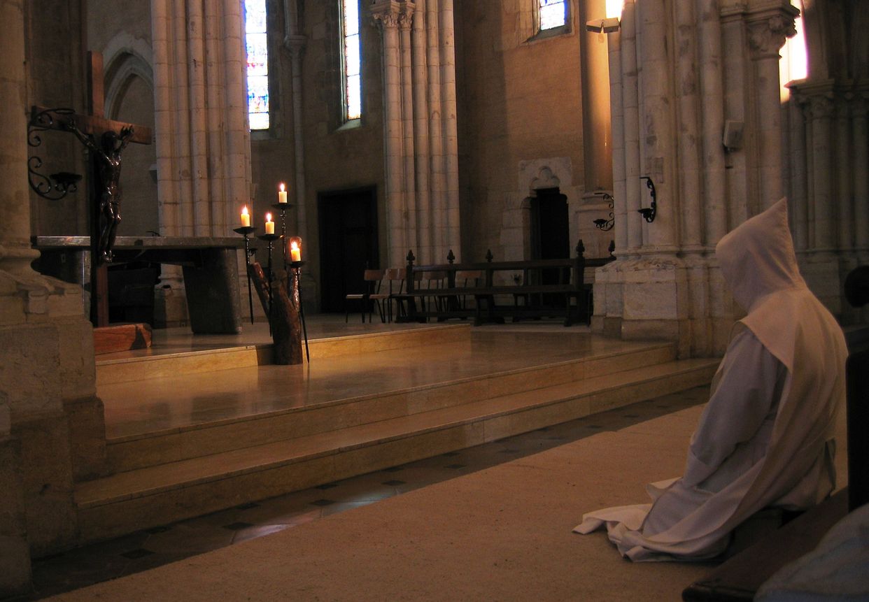 Un frère prie à genoux devant la Croix exposée le Vendredi Saint.