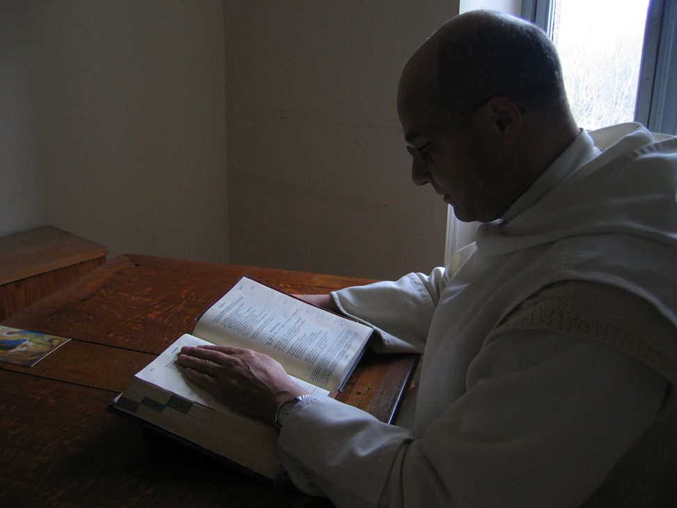 Un frère lit la Bible à son bureau, à la lumière du soleil.