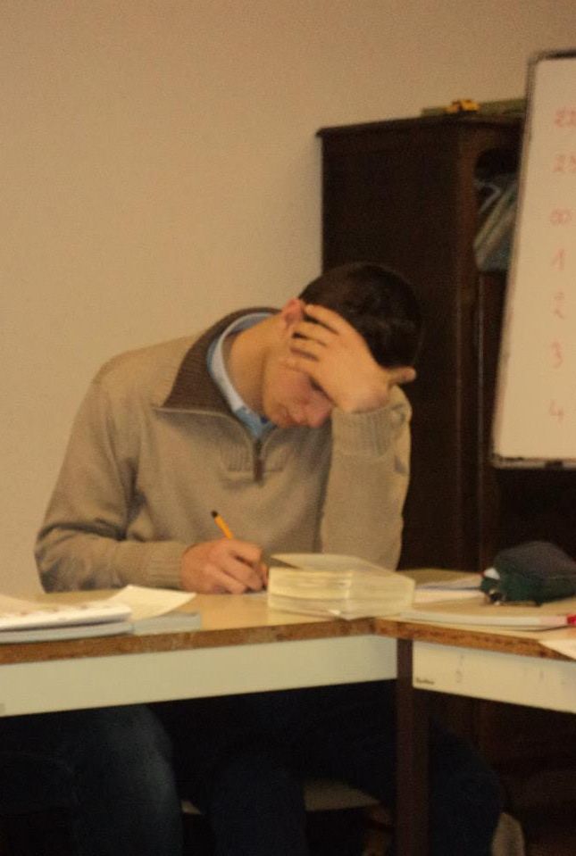 un jeune se tient la tête en prenant des notes