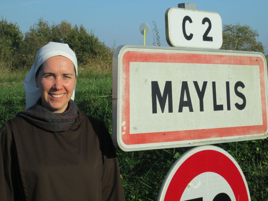 Une soeur en habit brun et voile blanc devant le panneau de Maylis