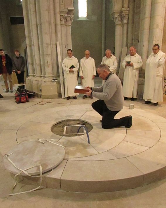 Un prêtre descend le reliquaire dans la fosse