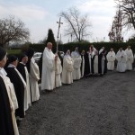 Frères et soeurs en rang autour de la croix de procession attendent la sortie de l'évêque