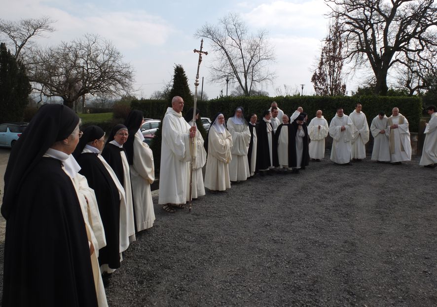 Frères et soeurs en rang autour de la croix de procession attendent la sortie de l'évêque