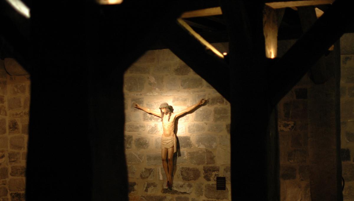 Christ en croix sur un mur de pierre au milieu de poutres