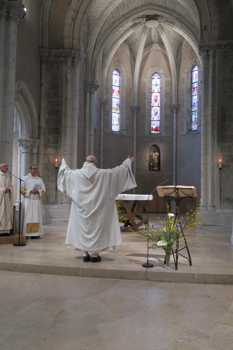 Fr Comlomban les bras levés devant l'autel