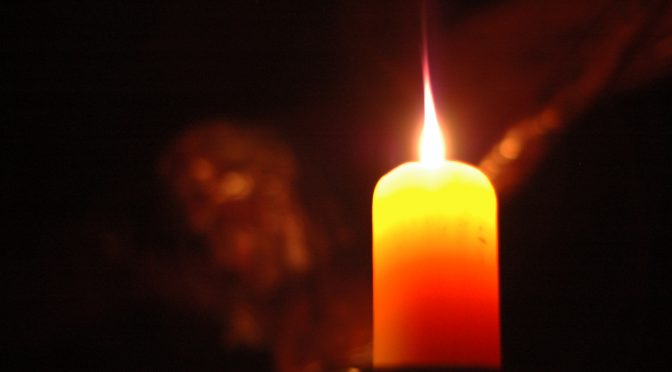 bougie avec le visage de Jésus crucifié en arrière-fond dans l'obscurité