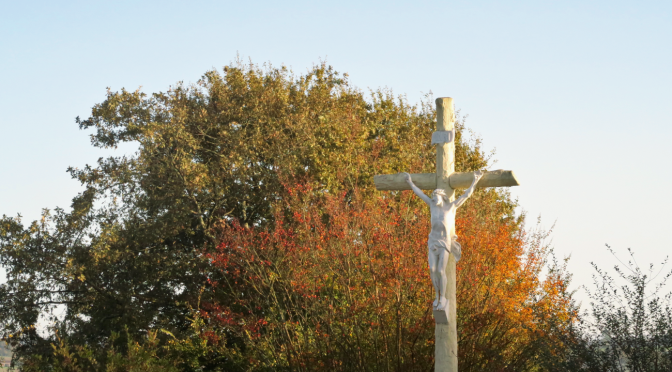 croix sur fond d'arbres aux couleurs de Toussaint